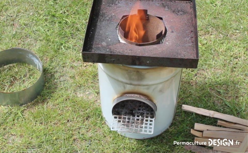 La technique du rocket stove est ici adaptée pour faire un barbecue ou un réchaud de plein air très efficace.